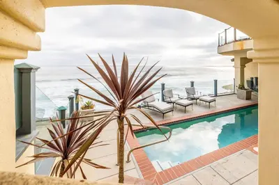 a palm tree in front of a swimming pool with the ocean at 4 Bedroom With Pool in Oceanside