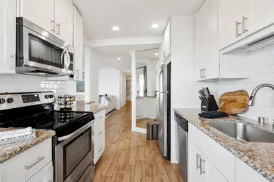 a white kitchen with a stove and a sink at Oceanfront La Jolla Cove Condo in San Diego