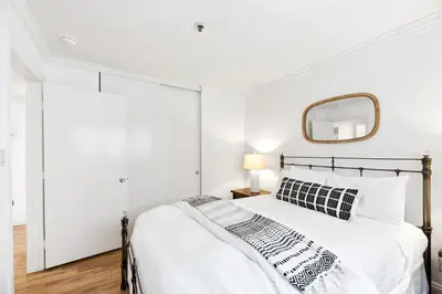 a white bedroom with a bed and a mirror at Oceanfront La Jolla Cove Condo in San Diego