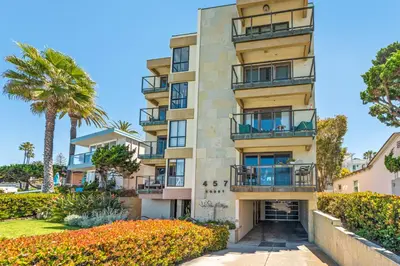 an apartment building with balconies and palm trees at Oceanfront La Jolla Cove Condo in San Diego