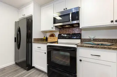 a kitchen with white cabinets and a black refrigerator at San Diego 4-Bedroom Home with POOL and Jacuzzi in Rancho Bernardo