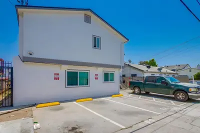 a green truck parked in a parking lot in front of a building at Stylish 1BR Near Downtown, Beaches & North Park in San Diego