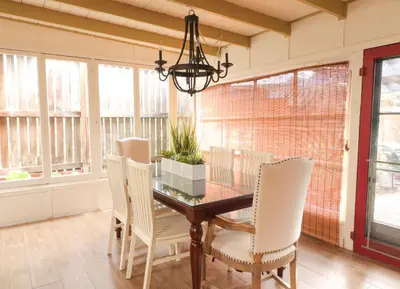a dining room with a wooden table and white chairs at Redwood Hollow Cottages in San Diego