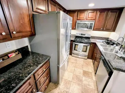 a kitchen with wooden cabinets and a stainless steel refrigerator at --Vacation First floor luxury condo La Jolla, Spa, Pool, Gym in San Diego