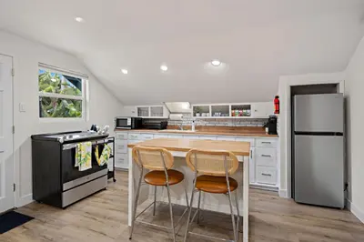 a kitchen with white cabinets and a black refrigerator at Ocean-View, Deck, Steps to Beach Dining and More in Solana Beach