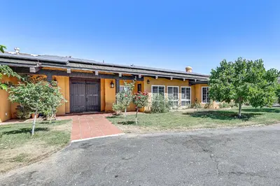 a yellow house with a garage and trees in front of it at Stunning Valley and Mtn Views Elegant Temecula Home in Temecula