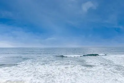 a beach with a small wave in the ocean at Luxury Oceanfront Home- Upper in Oceanside