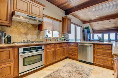 a kitchen with wooden cabinets and stainless steel appliances at Luxury Oceanfront Home- Upper in Oceanside