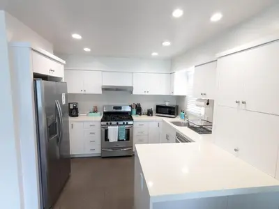 a kitchen with white cabinets and a stainless steel refrigerator at Steps from Ocean! Ocean and Bay Views! Rooftop Deck! Two-Car Garage! Renovated! in San Diego