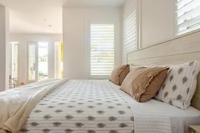 a bedroom with a large bed with white walls and windows at Private Encinitas Casita & Patio in Encinitas