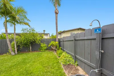 a fence with a palm tree in a yard at Designer Home with Yard -Walk to Beach, Shops and More in Solana Beach