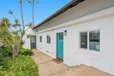a white house with a blue door and palm trees at Designer Home with Yard -Walk to Beach, Shops and More in Solana Beach