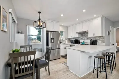 a kitchen with white cabinets and a table and chairs at Seabreeze 1BR, Walk to Sand, Pet Friendly, Parking, Fire Pit Access in Carlsbad