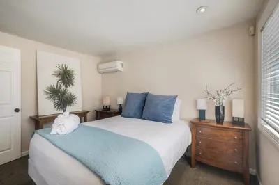 a bedroom with a large bed with blue pillows at Oceanside Bungalow, Walk to Beach & Pier, Private Hot Tub, Beach Gear in Oceanside