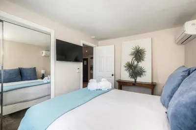 a bedroom with a large white bed and a mirror at Oceanside Bungalow, Walk to Beach & Pier, Private Hot Tub, Beach Gear in Oceanside