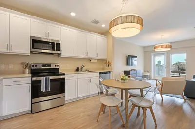 a kitchen with white cabinets and a table with chairs at NEW LUX Modern Retreat Views Parking Workspaces in San Diego
