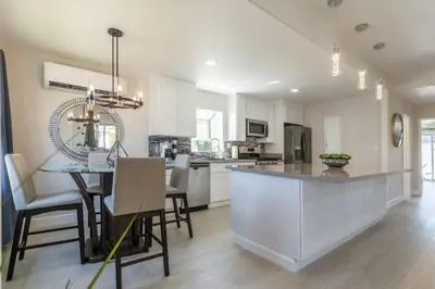 a kitchen and dining room with white cabinets and a table at Allure Retreat in San Diego