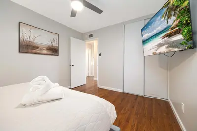 a bedroom with a white bed and a flat screen tv at Central Backyard Oasis Villa in San Diego