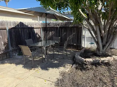 a table and chairs with an umbrella next to a tree at Cozy cottage in San Diego