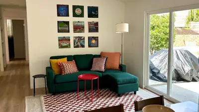 a living room with a green couch and a red stool at San Diego Oasis Fire Pit, Putting Green, Near Everything in San Diego