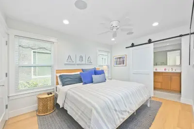 a white bedroom with a bed with blue pillows at Sail & Sea in Newport Beach