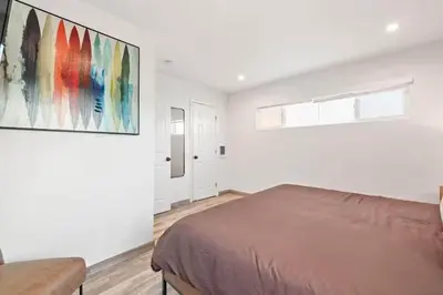 a bedroom with a bed and a painting on the wall at Ocean Views Steps to Beach Rooftop Firepit in San Diego