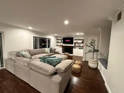 a living room with a large couch and a television at OC Heated Pool,Fire Pit,Spa,BBQ,Disney,Beaches in Mission Viejo