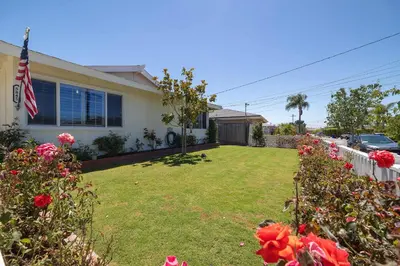 a house with a flag in a yard with roses at 10 min to Beach Central Villa in San Diego