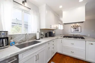 a kitchen with white cabinets and a sink and a window at 10 min to Beach Central Villa in San Diego