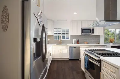 a kitchen with white cabinets and a stainless steel refrigerator at Ocean Views 2 Kitchen Living area Villa in San Diego