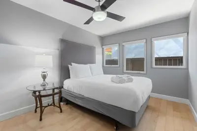 a bedroom with a bed with a ceiling fan and windows at Seaside Spiral in San Diego