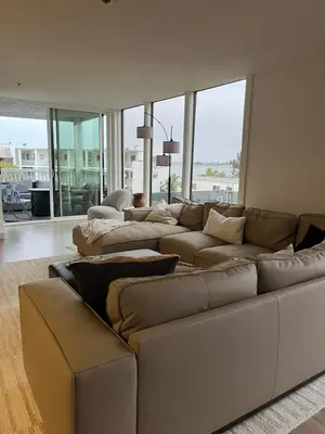 a living room with a large couch and large windows at Sail Bay Condo in PB Bay View close to the Ocean! 30 day stay is required in San Diego