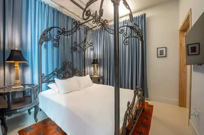 a bedroom with a white bed and blue curtains at Hotel Narcissus - Room 2 in San Diego