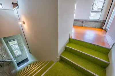 a stairway with green carpet and stairs in a building at Hotel Narcissus - Room 6 in San Diego