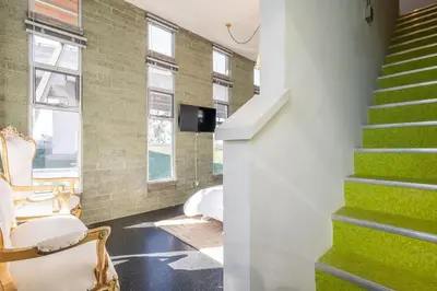a living room with green stairs and a tv at Hotel Narcissus - Room 6 in San Diego