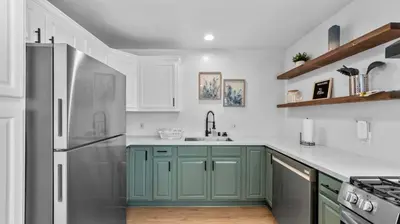 a kitchen with green cabinets and a stainless steel refrigerator at Stylish Apartments in Mission Hills with Outdoor Space in San Diego