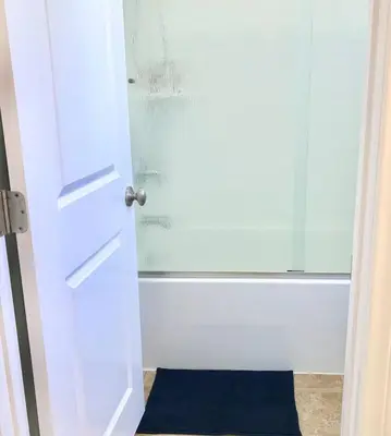 a white door with a blue rug next to a shower at Corporate Housing, Vacation Rental in Irvine in Irvine
