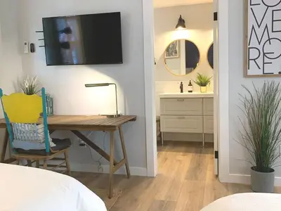 a bedroom with a desk with a television on the wall at New cozy studio 2 queen beds kitchen walk to water! in San Diego