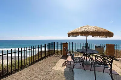 a table and chairs with an umbrella and the beach at Top of the Wave - DMST31 in Solana Beach