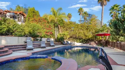 a swimming pool with chairs and an umbrella at Two Estates w Pools Hot Tubs Game Rooms Valley Views Tennis Court Near Beaches Wineries in Escondido