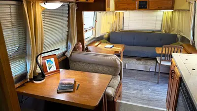 a living room with a table and a desk with a laptop at Retro Star-Wagon, Ocean Breez at Studios in Oceanside