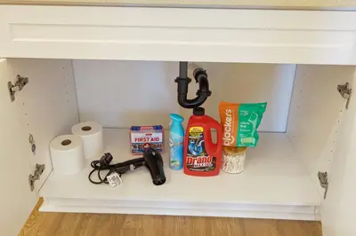 a shelf under a bathroom sink with toilet paper and cleaning products at Luxury Living in N Park, 2BR, King Beds, Parking in San Diego