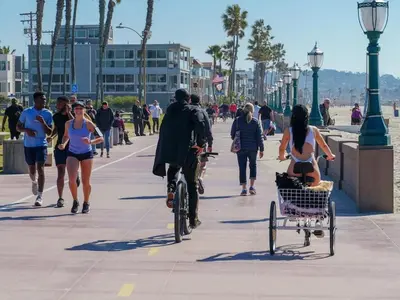 a group of people walking and riding bikes down a sidewalk at Tourmaline Beach Cottage North -Steps to Ocean, AC in San Diego