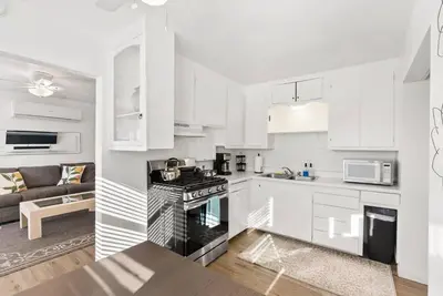 a kitchen with white cabinets and a stove top oven at Tourmaline Beach Cottage North -Steps to Ocean, AC in San Diego