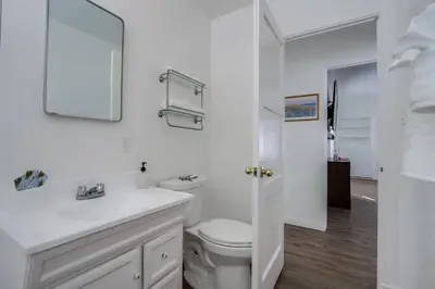 a white bathroom with a toilet and a sink at Tourmaline Beach Cottage North -Steps to Ocean, AC in San Diego