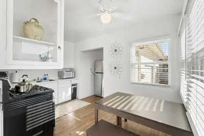 a kitchen with a stove and a table in it at Tourmaline Beach Cottage North -Steps to Ocean, AC in San Diego