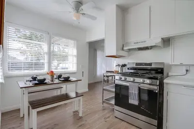 a kitchen with white cabinets and a black stove at Tourmaline Beach Cottage North -Steps to Ocean, AC in San Diego