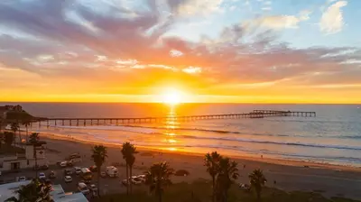a sunset over a beach with a pier at Stunning OB Ocean View Stay in San Diego