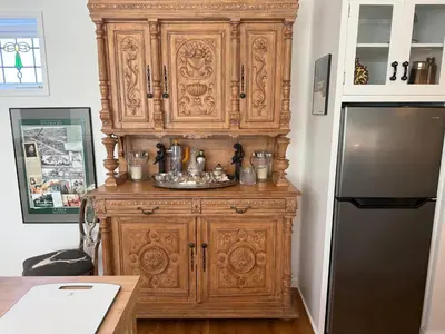 a large wooden cabinet in a kitchen next to a refrigerator at La Jolla Carriage House in San Diego
