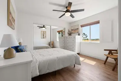 a white bedroom with a bed and a ceiling fan at Luxury Oasis Compound with Hot Tub with 3 Homes in Escondido